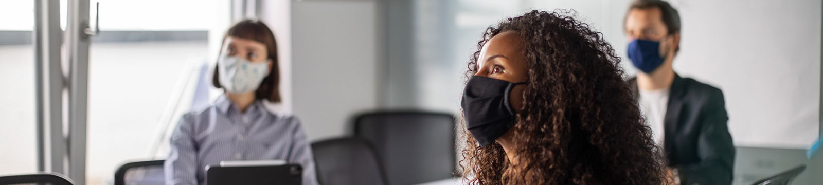 people in an office board room wearing masks
