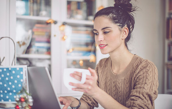 Lady using her laptop computer while drinking coffee